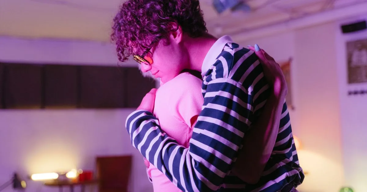 A young couple lovingly embracing in a cozy indoor environment with soft lighting.