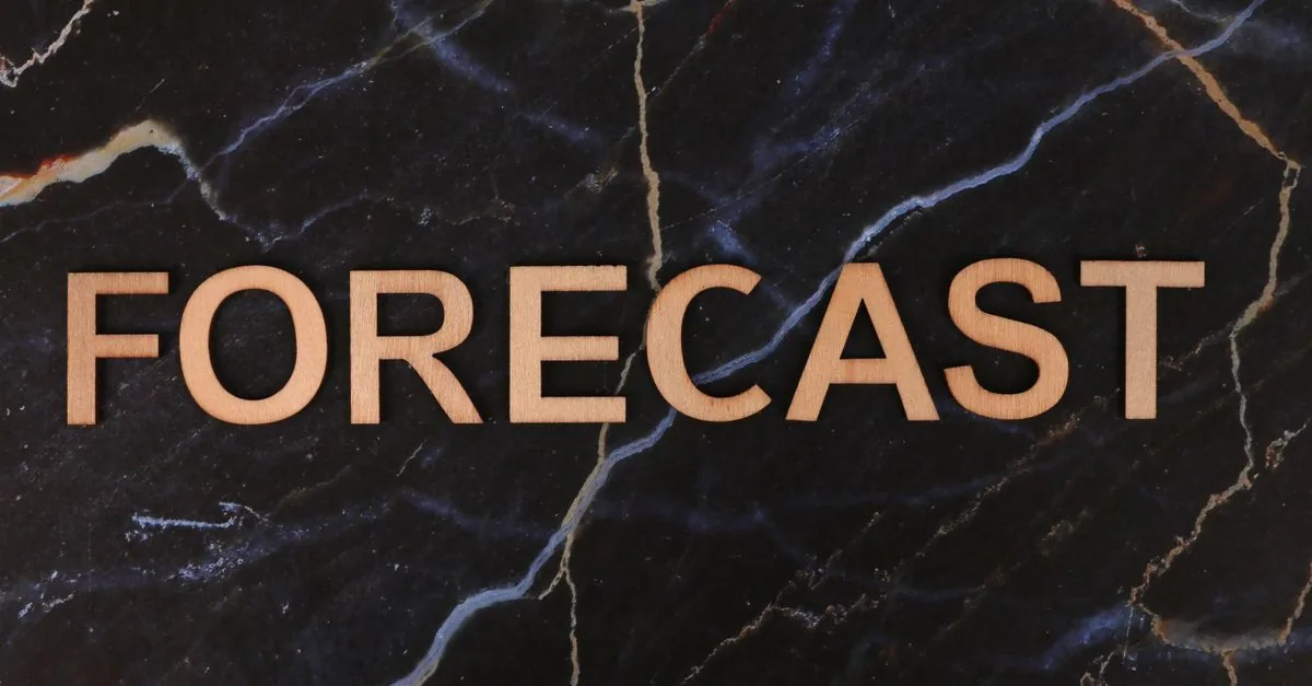 The word 'FORECAST' in wooden letters on a dark marble background.